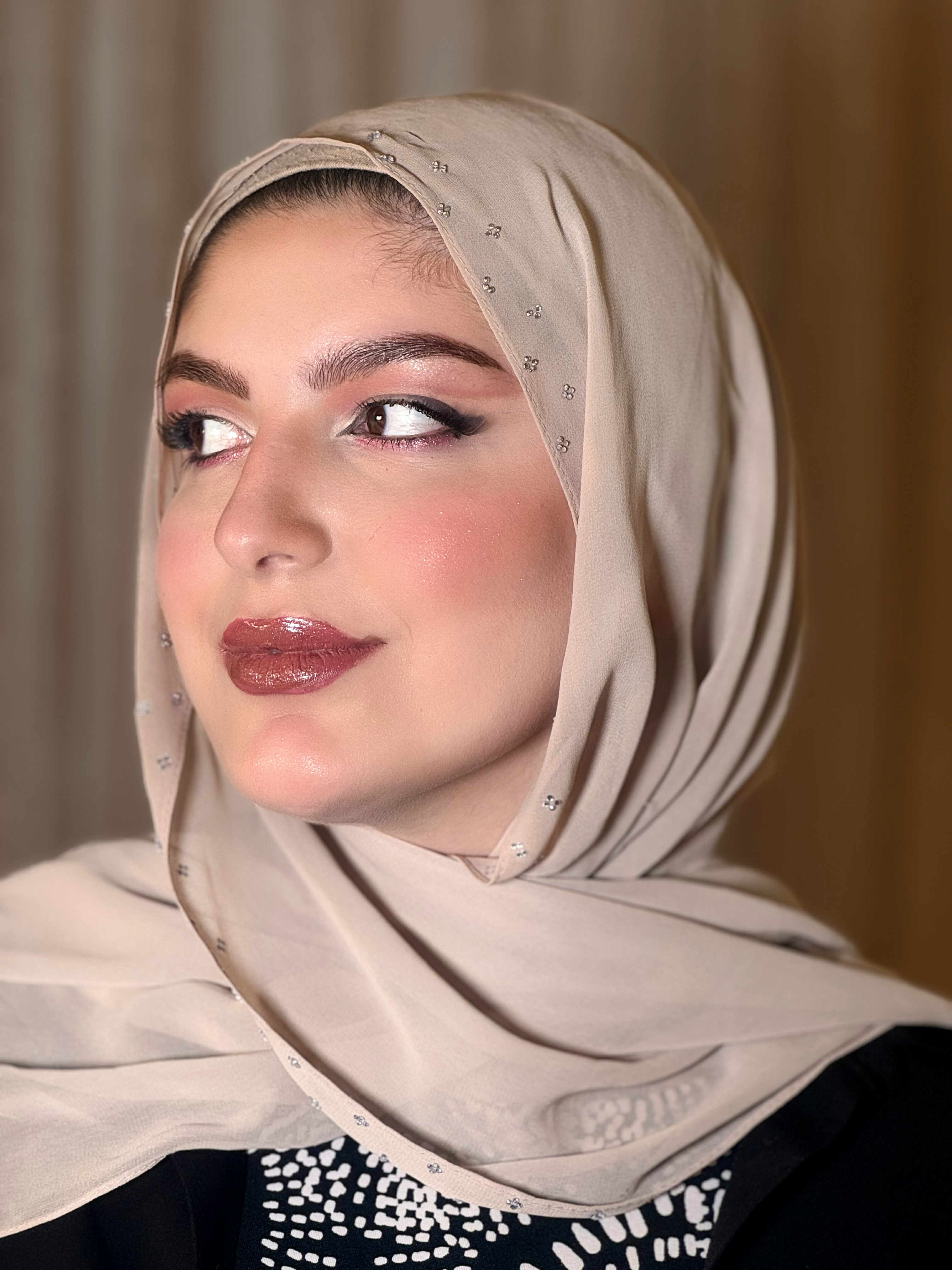 Glamorous makeup with winged eyeliner and burgundy lips in embellished beige hijab