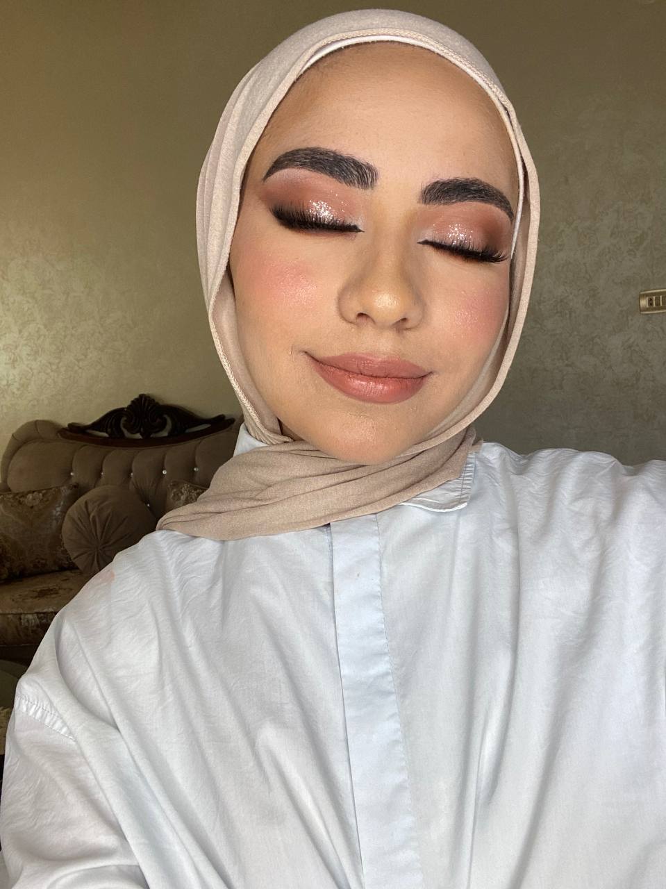 Dramatic evening makeup with shimmer eyeshadow and nude lips in beige hijab